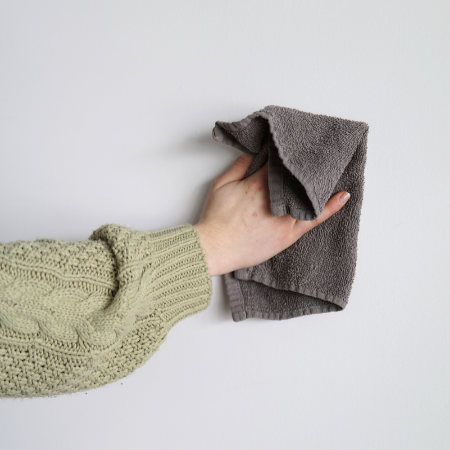 Main avec Chiffon nettoyant le mur